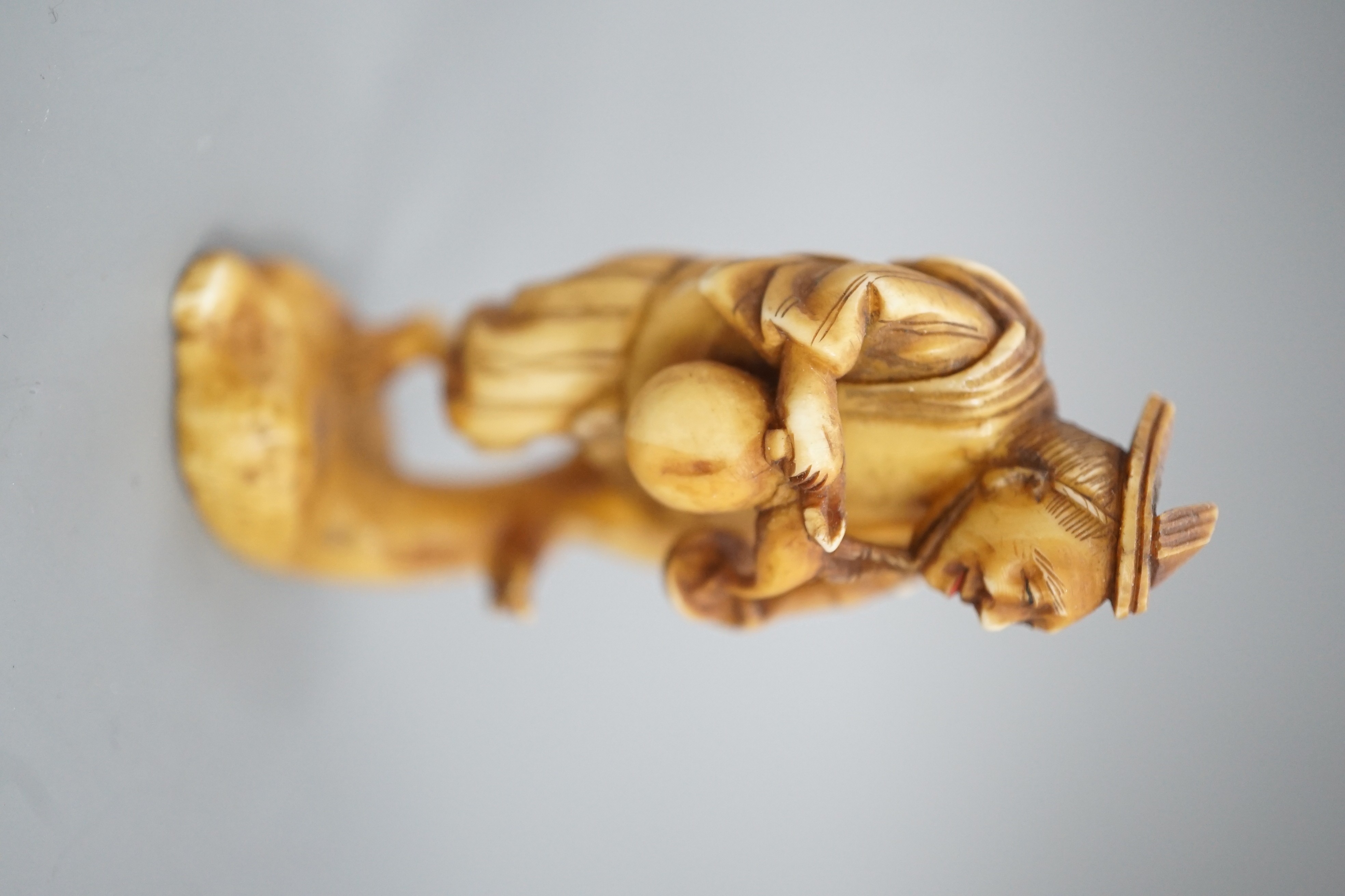 A Japanese ivory okimono of a man dancing and pouring wine from a flask, signed, Meiji period, 7cm